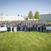 A group of happy people standing outside of a large BorgWarner manufacturing plant.