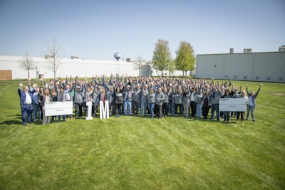 A group of happy people standing outside of a large BorgWarner manufacturing plant.