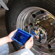 A man checks a tire sensor with a tablet.