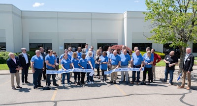 A group of people with a cut ribbon standing in front of a building.