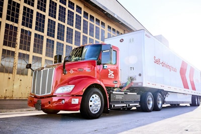 A red Class 8 truck with a white trailer that reads, 'Self-driving truck'