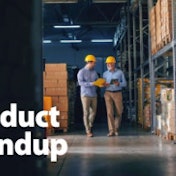 Two men walking down a warehouse aisle.