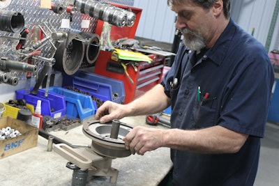 Man working on a fan clutch on a table.
