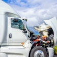 A white truck with the hood up for service under a partly cloudy blue sky.