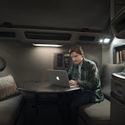 A man works at a retractable desk in a Volvo truck.