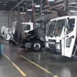 The inside of a commercial truck repair shop with four trucks being repaired.