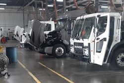 The inside of a commercial truck repair shop with four trucks being repaired.