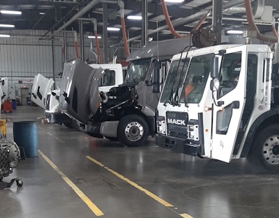 The inside of a commercial truck repair shop with four trucks being repaired.