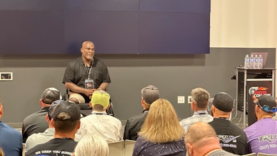 Col. Greg Gadson, a double amputee and veteran, sits in front of a room talking to business owners.