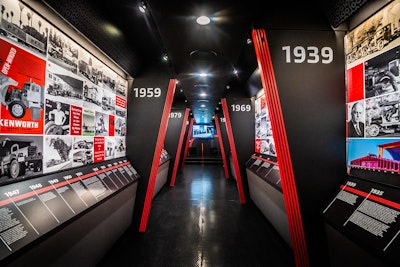 Exhibits inside the Kenworth 100th anniversary trailer, which is wallpapered with Kenworth advertisements and photographs.