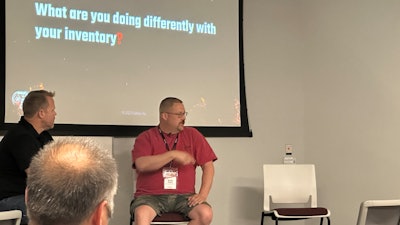 Two men sitting in front of a presentation screen.