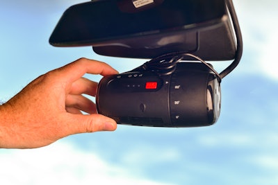 A hand adjusting a dash camera.