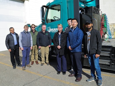 A group of men standing in front of a teal truck.