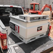 A fuel tank in the back of a pickup truck on a construction site.
