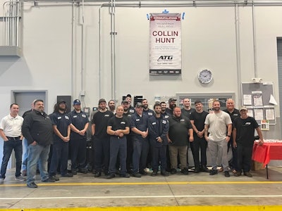 ATG's Raynham, Massachusetts, staff stands under a banner congratulating technician Collin Hunt.