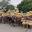 A group of brown-clad UPS workers hold picket signs outdoors.