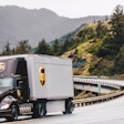 A UPS truck and trailer going down a mountain road.