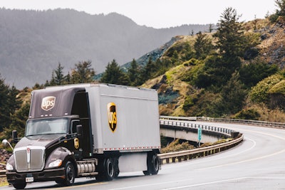 A UPS truck and trailer going down a mountain road.