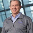 A man in an Eaton-branded gray pullover and blue business shirt.