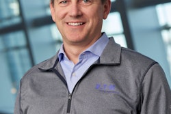 A man in an Eaton-branded gray pullover and blue business shirt.