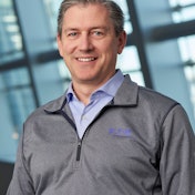 A man in an Eaton-branded gray pullover and blue business shirt.