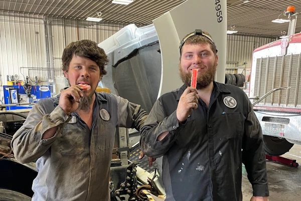 Two men eating popsicles in a garage