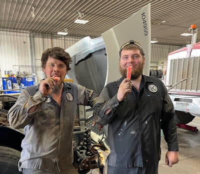 Two men eating popsicles in a garage