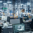 A room of people working on computers at a factory.
