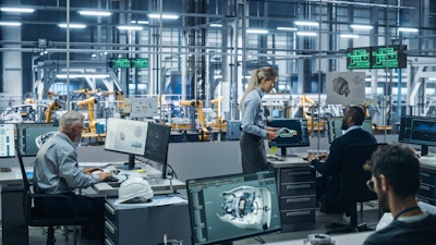 A room of people working on computers at a factory.