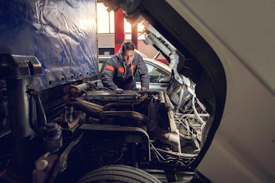 A man looks under the hood of a truck.
