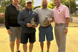 Two men holding awards standing with two other men outdoors at dusk.