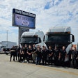 Tom's Truck Center team in front of sign and trucks