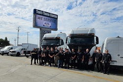Tom's Truck Center team in front of sign and trucks