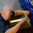 A technician adjusts an ADAS sensor on the front of a truck.