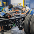 Vehicle chassis being assembled by two technicians