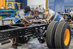 Vehicle chassis being assembled by two technicians