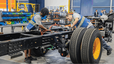 Vehicle chassis being assembled by two technicians