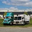 A teal Volvo Electric truck and a Mack electric refuse vehicle in front of Kriete Truck Center.