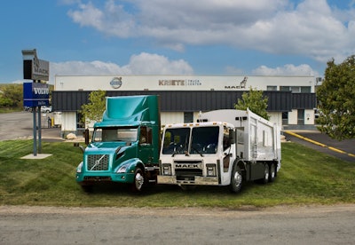 A teal Volvo Electric truck and a Mack electric refuse vehicle in front of Kriete Truck Center.