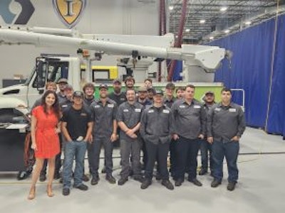 A group of people in front of a bucket truck.