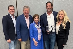 A group of people surround a man holding an award