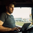 Truck driver on laptop in a truck cab