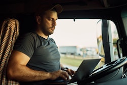 Truck driver on laptop in a truck cab