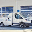 A white TA Truck Service truck in front of two garage bays.