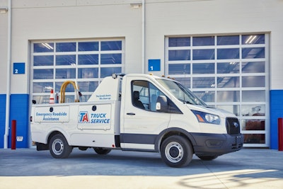 A white TA Truck Service truck in front of two garage bays.