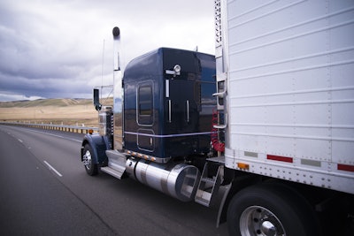 A tractor trailer driving over an elevated roadway.