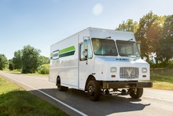 An Xos Stepvan in Penske livery driving down a road.
