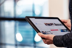 A tablet displaying the Volvo Connect fleet management portal held in a pair of hands in a brightly lit room.