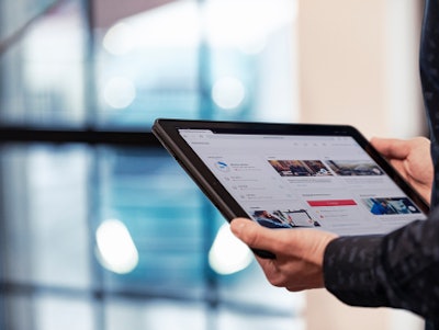 A tablet displaying the Volvo Connect fleet management portal held in a pair of hands in a brightly lit room.