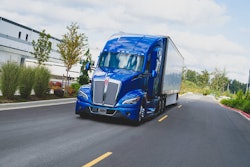 A blue Kenworth T680 hauling a trailer.
